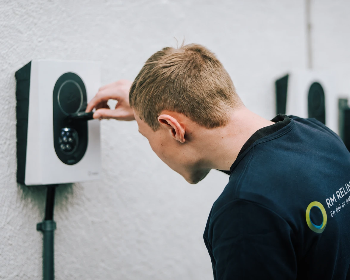Smarta hem och modern teknik i Stockholm, elektriker installerar laddbox för elbil på husfasad.